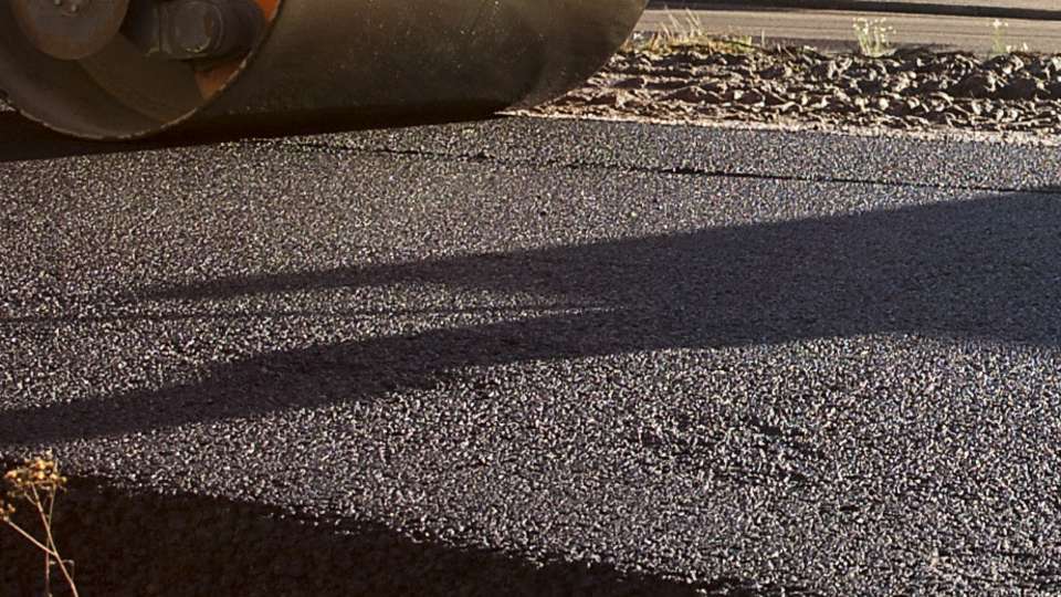 Närbild av svart asfalt under en vält.