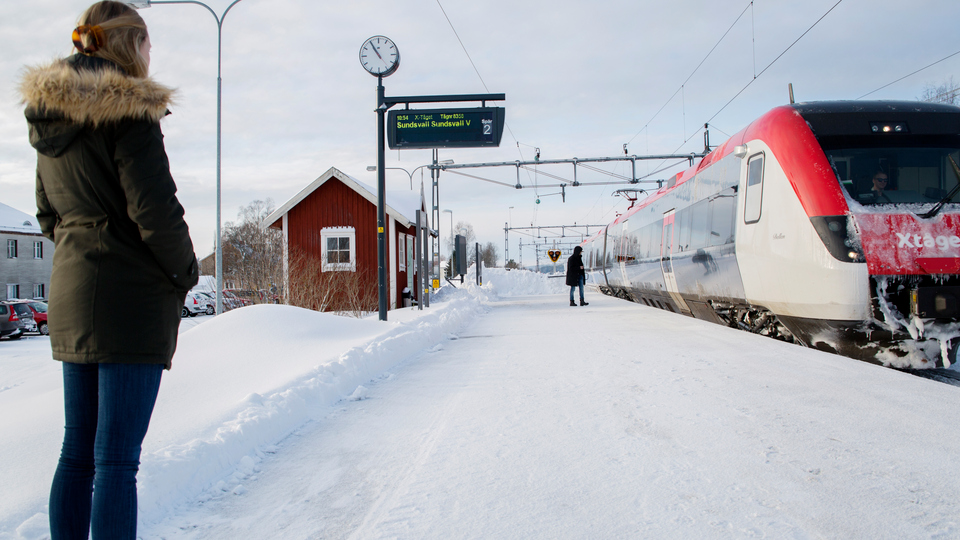 X-tåget vid Gnarps station. Vinter och snö, en kvinna står i förgrunden.