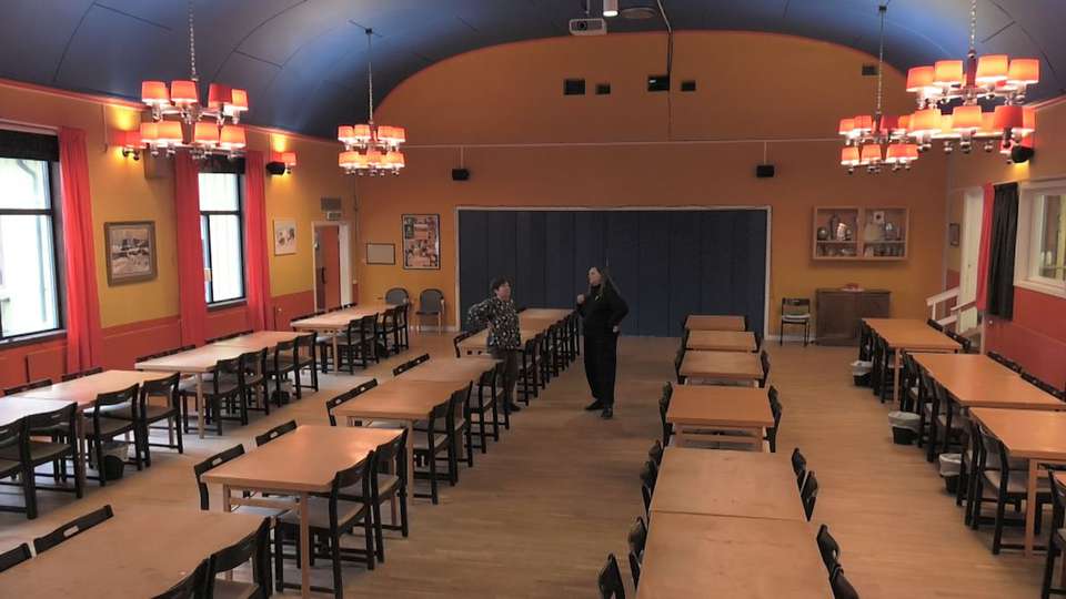 Ett stort rum möblerat med långa rader av bord och stolar.