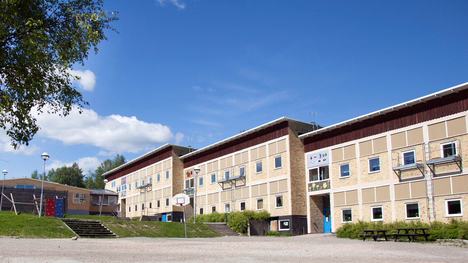Bergsjö skola i Bergsjö, skolgård i förgrunden med bänkar och en basketkorg