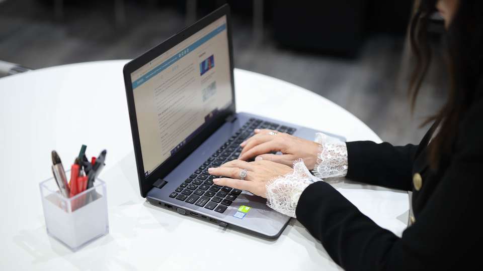 En kvinna sitter vid sin bärbara dator i väntan på ett webbinarium.