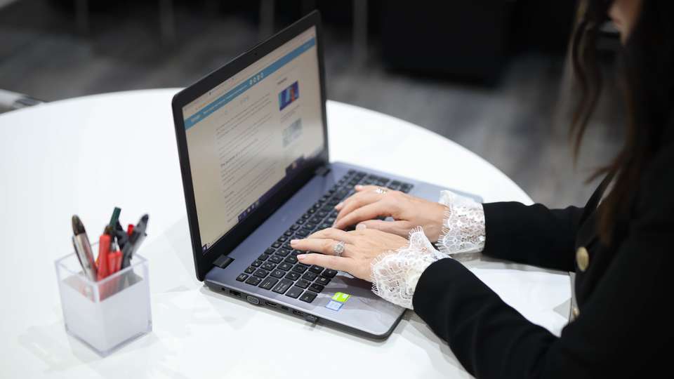 En kvinna sitter vid en dator inför ett webbinarium.