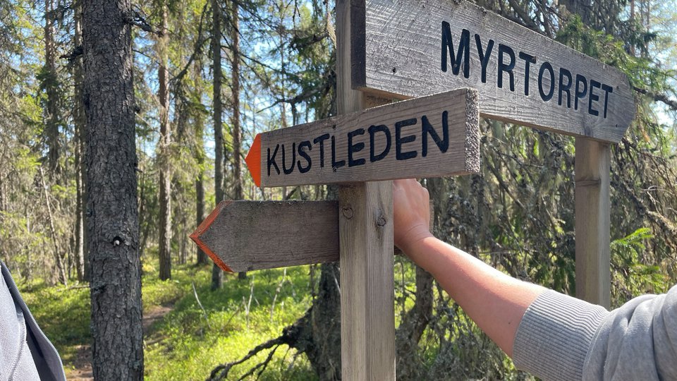Träskylt i skogen med texten "Kustleden".