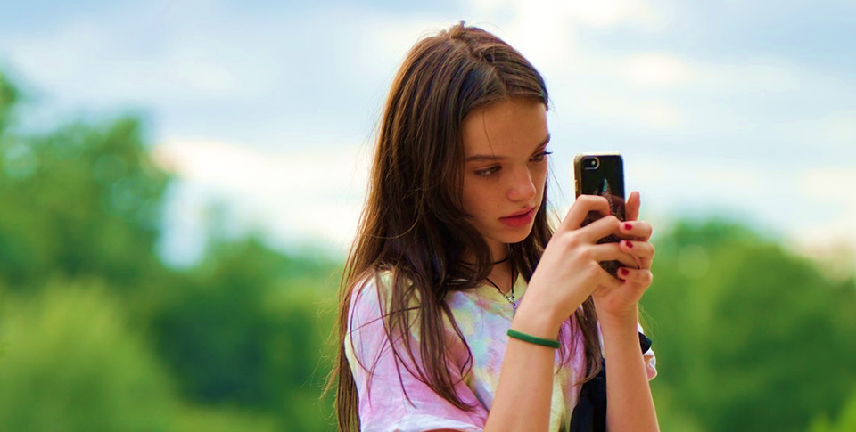 En ung flicka som tittar på sin mobiltelefon.