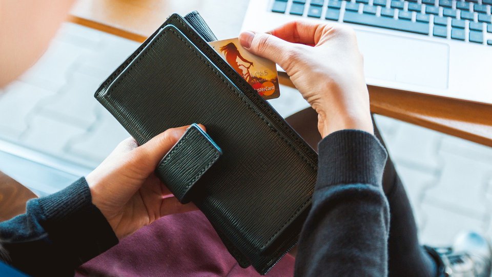 En hand drar ett betalkort ur en plånbok.
