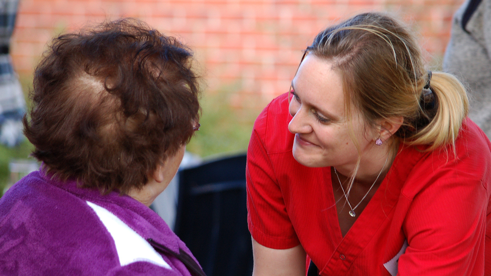 En yngre kvinna böjer sig fram och ler mot en äldre kvinna.