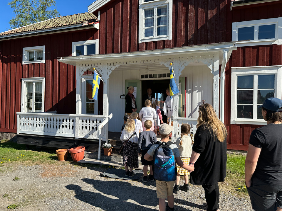 Elever och lärare går på led in i en gammal skolbyggnad.