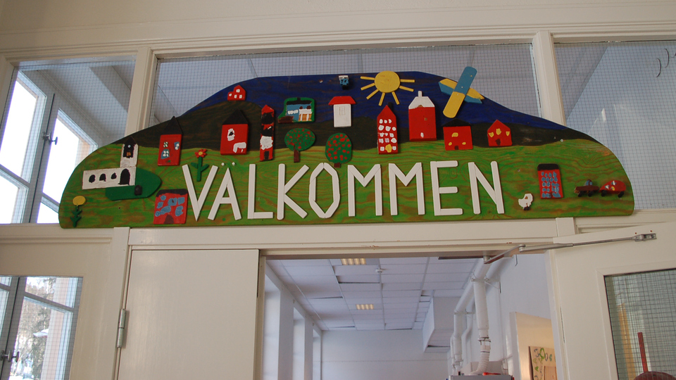 Skylt över dörr inomhus med texten "Välkommen" på Arthur Engbergskolan i Hassela.