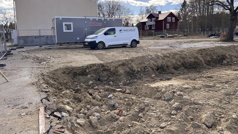 Markschakt med minibuss och byggnad i bakgrunden