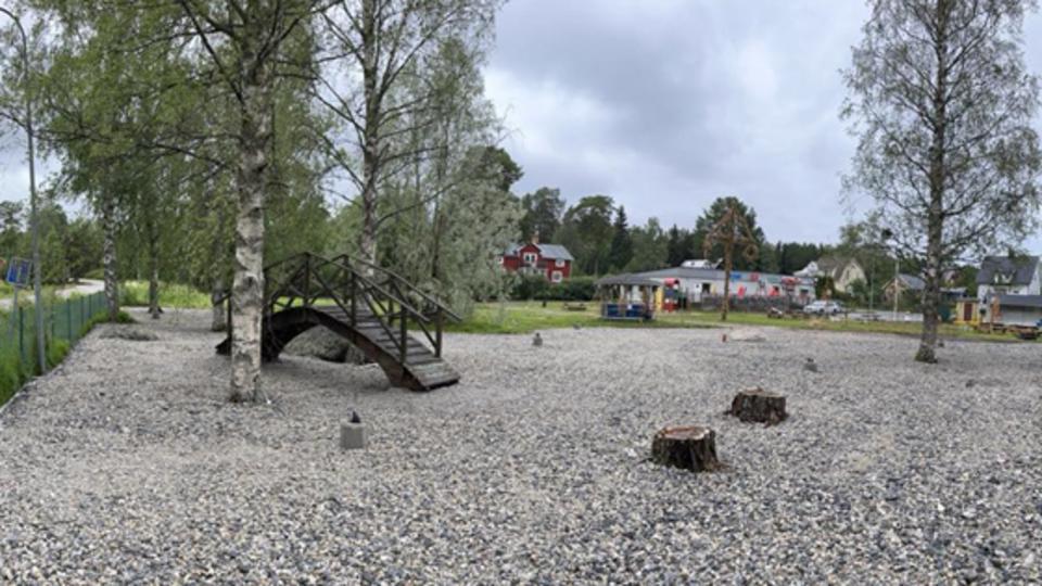Ett inhägnat område med grus och några träd.