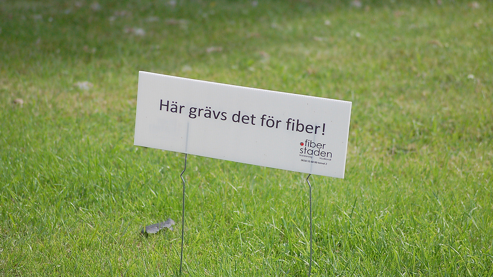 Skylt där det står - "Här grävs det för fiber! Fiberstaden " står på en gräsmatta