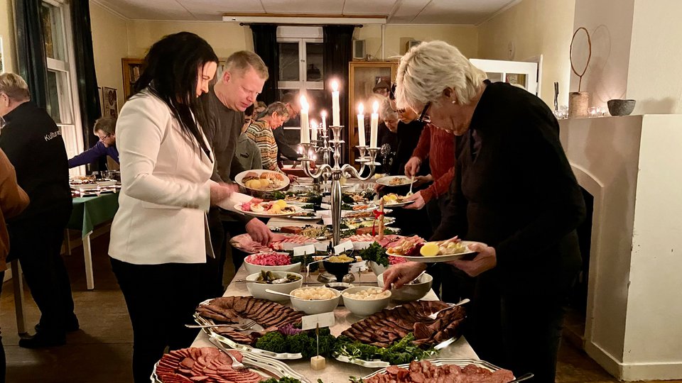 Flera personer tar mat fån ett julbord.