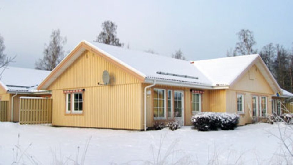 Gulaktig träbyggnad inbäddad i snö.
