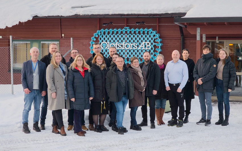 En grupp människor står framför ett kontor med en skylt som det står Oloffors AB på. Det är snö på marken och hustaket.