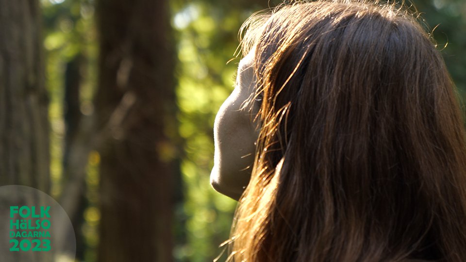 En kvinna i skogen med ansiktet vänt mot solen.