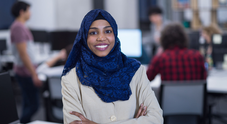 Portrait of young muslim african american female software developer with blue scarf standing at modern startup office