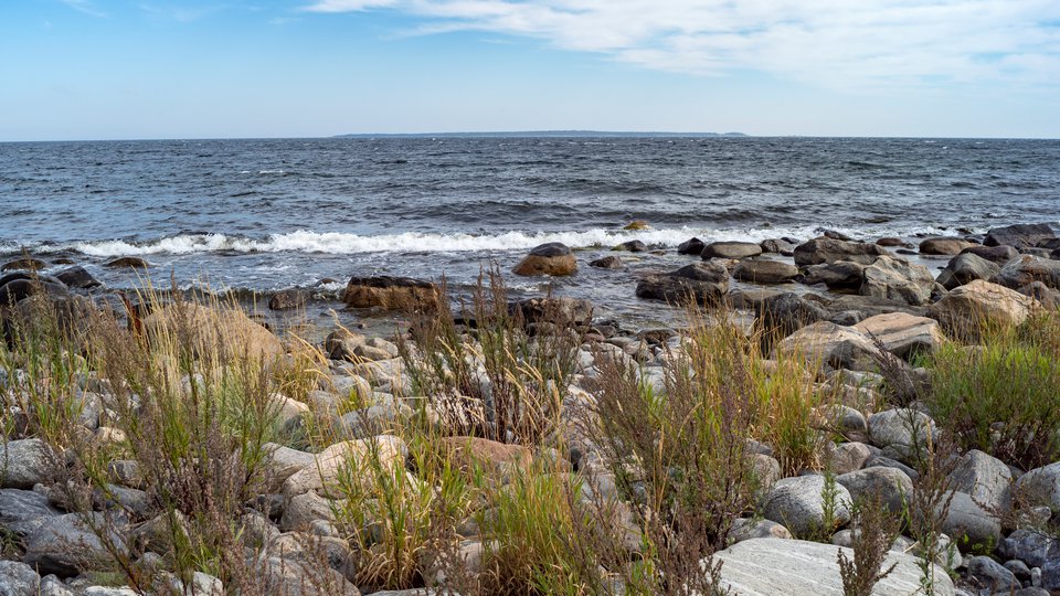 Stenar och havet med en större ö i bakgrunden