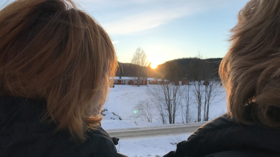 Två kvinnor tittar på solnedgången i Bergsjö en vintereftermiddag.