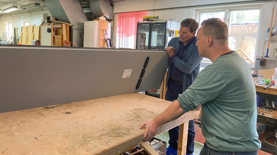 Stig Eng inspekterar en lös takplåt inne i Leax Byggs verkstad. Ägaren Lars Brusell förklarar.