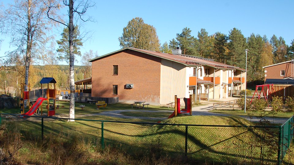 Tegelgavel, staket och lekplats vid förskola.