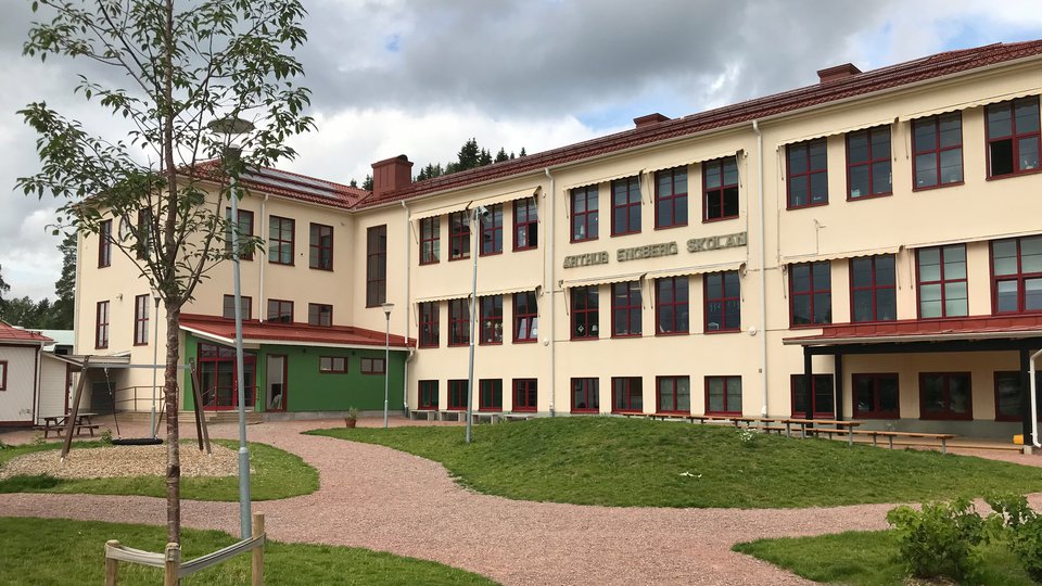 En skolbyggnad med gräs och grusgångar framför.