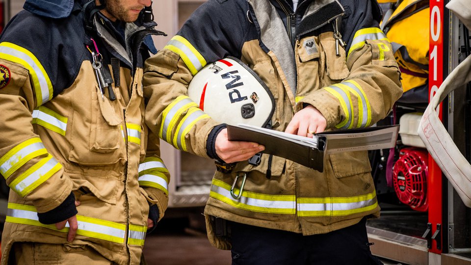 Två brandpersonal diskuterar brandbekämpning i fält.