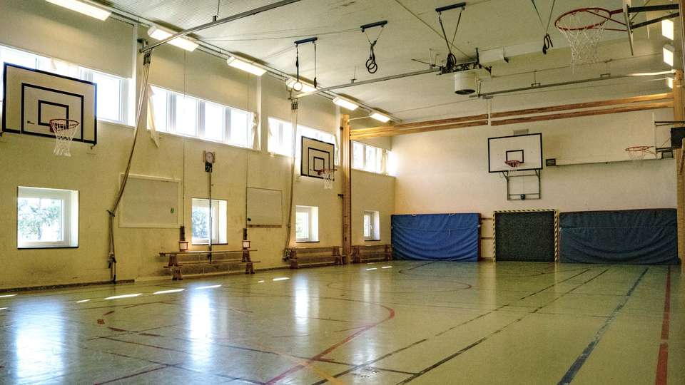 Idrottssal med flera basketkorgar, ringar i taket och stora dynor efter kortsidan. Bergsjö skola i Bergsjö skola.