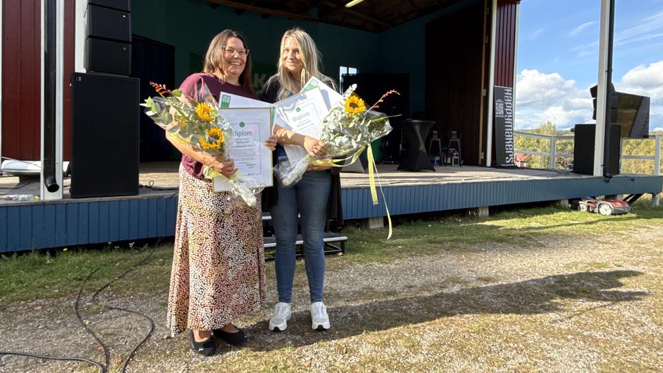 Två kvinnor med blommor framför en scen.