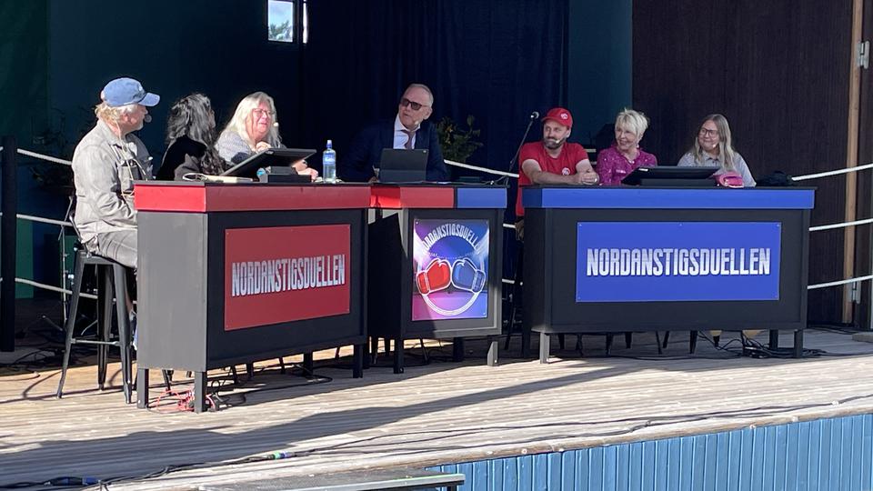 Sju personer i en panel på en scen.