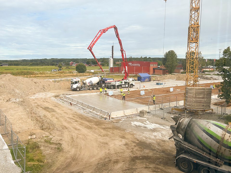 Byggarbetare gjuter betongplatta på skolbygge.