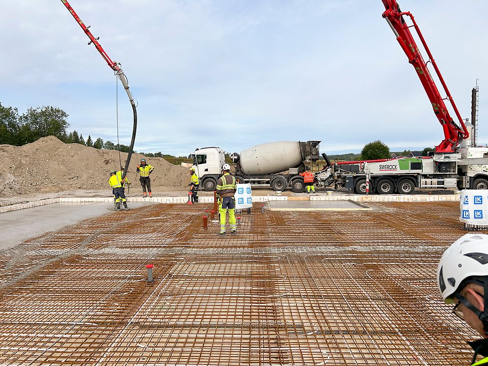 Byggarbetare gjuter betongplatta på skolbygge.